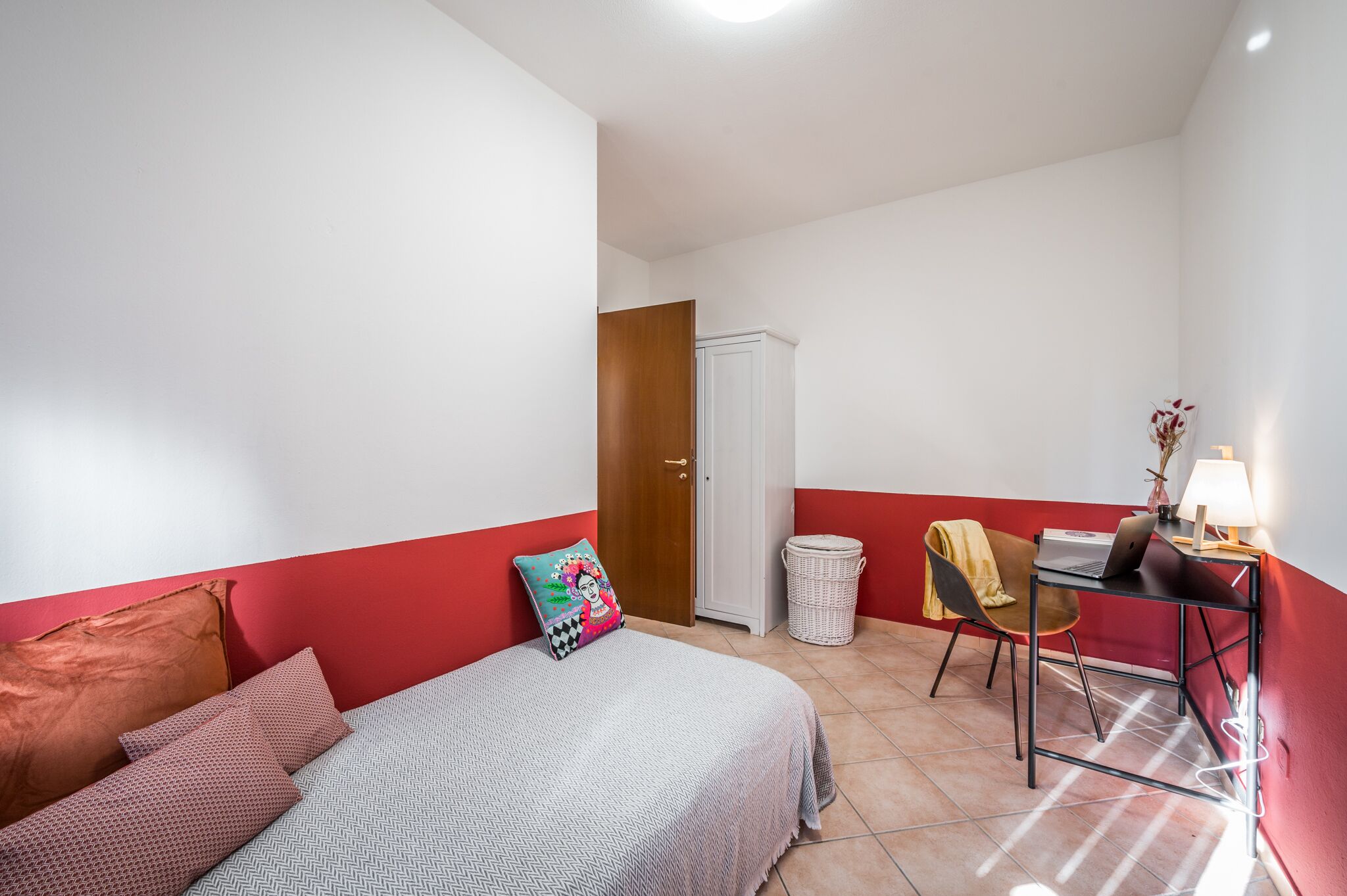 Ein Schlafzimmer mit Bett, Schreibtisch, Stuhl und Lampe.