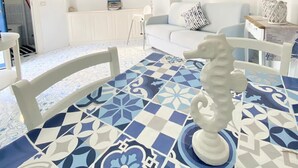 A modern living room with a white sofa, a dining table with a blue and white patterned tablecloth, and a decorative seahorse centerpiece. - Arime Apartment
Elegance and Tradition a Stone's Throw from the Sea" (Lacco Ameno)
