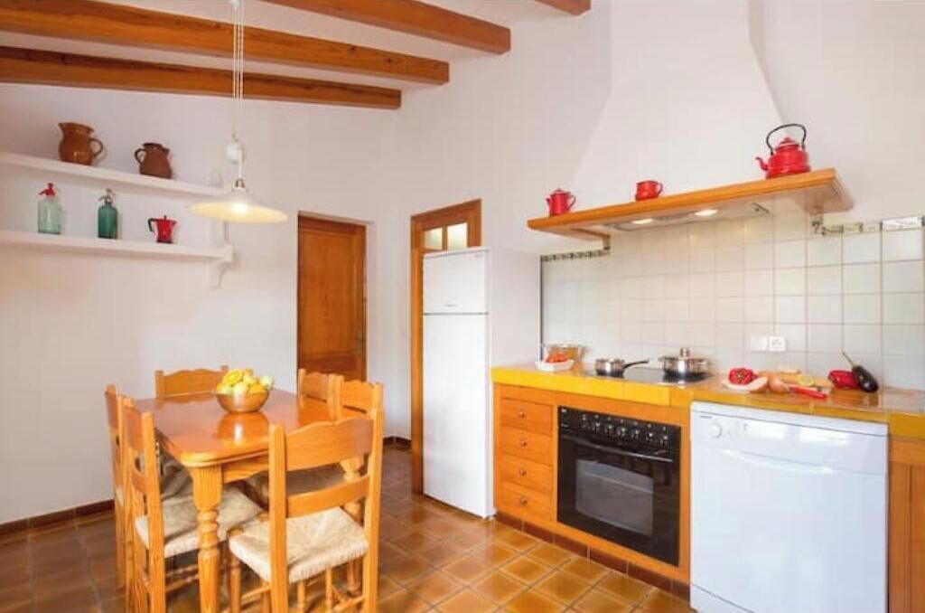 A kitchen with wooden cabinets, a dining table with chairs, a refrigerator, and a dishwasher.