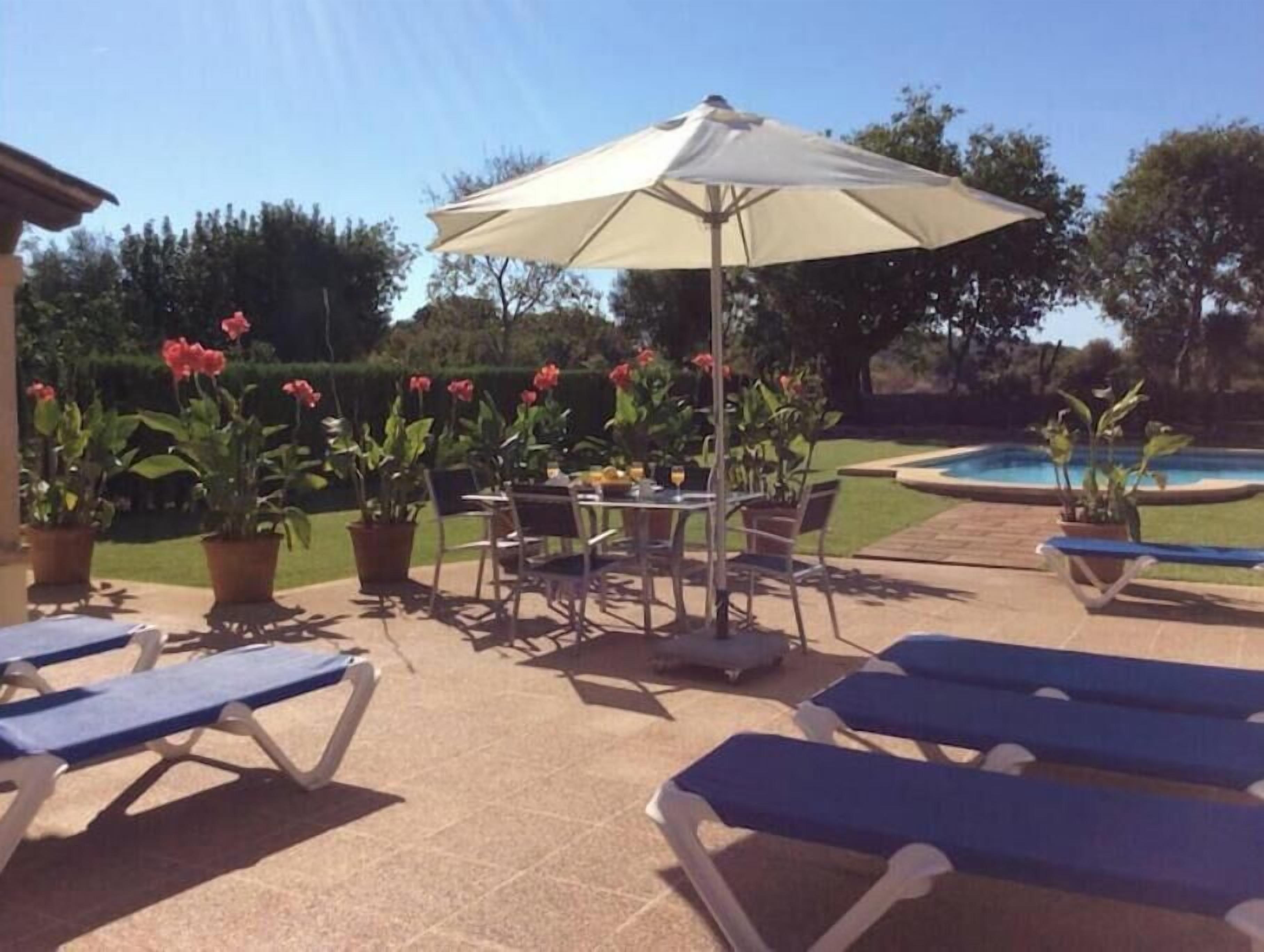 An outdoor patio area with lounge chairs, a table, and an umbrella.