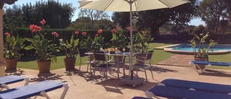 Un espace extérieur aménagé en terrasse, avec des chaises longues, une table et un parasol.