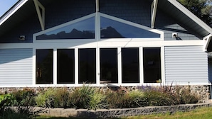 A house with a large bay window, stone foundation, and a well-maintained garden.