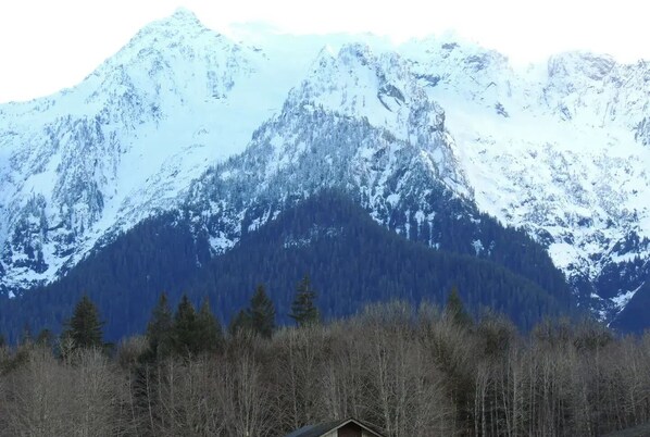 A mountain landscape with snow-covered peaks and a forested area in the foreground. - Darrington Majestic White Horse Mountain Home
(Arlington)