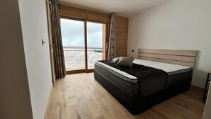 A bedroom with a large bed, a sliding glass door to a balcony, and wooden flooring. - 2nd floor, view mountain, balcony, tv, 81m², La Plagne (Aime)