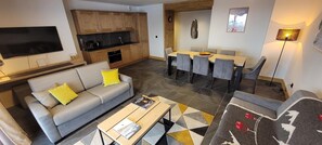 Een moderne woonkamer met een bank, salontafel en een eethoek met stoelen.