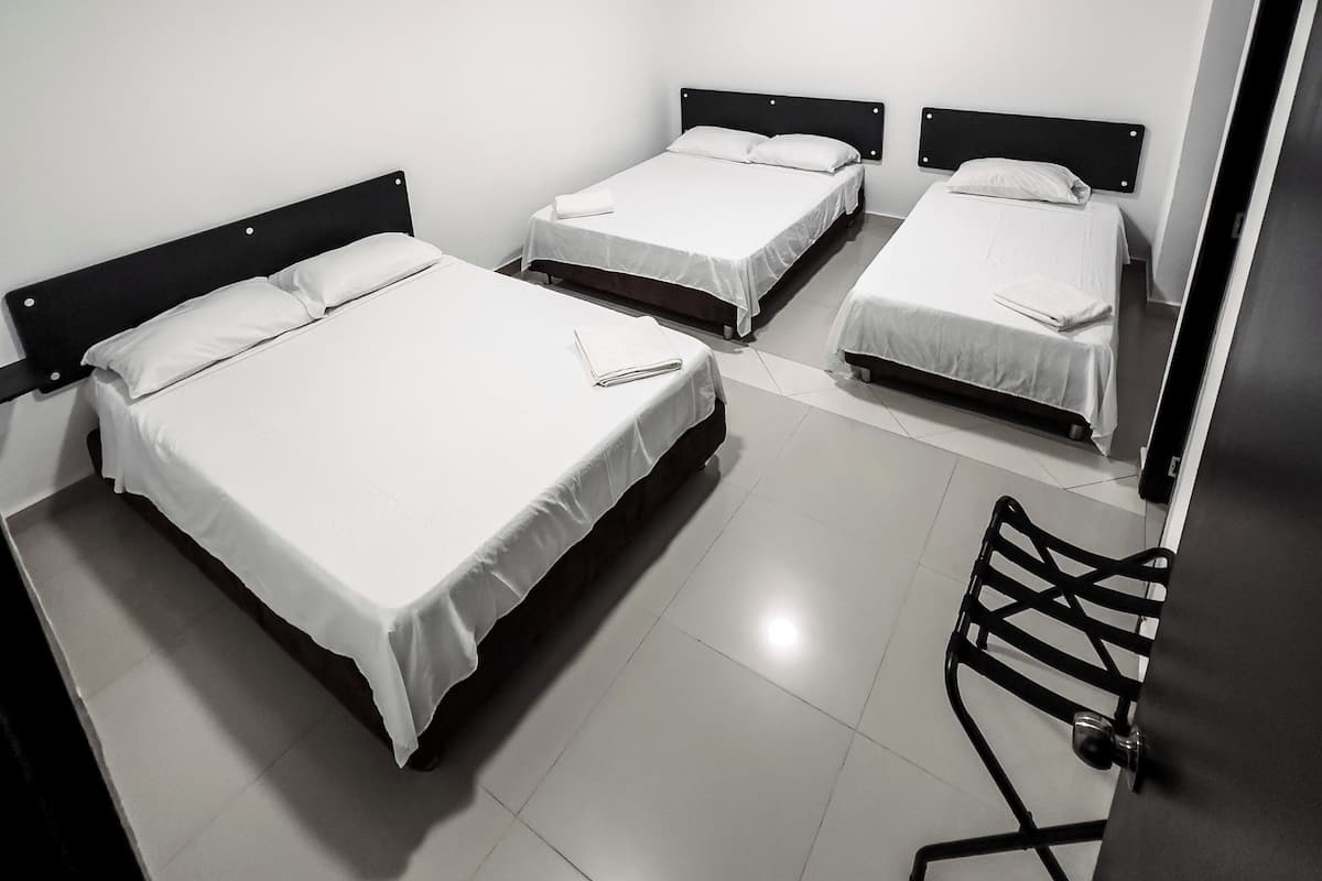 Una habitación con tres camas individuales, una silla y un escritorio.