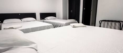 Habitación de hotel con dos camas, un armario y una puerta.