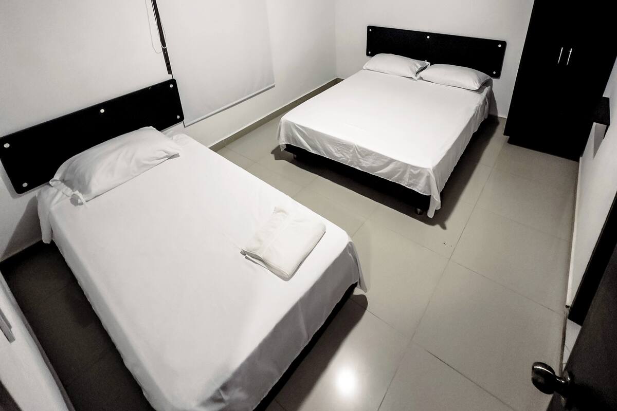 Una habitación con dos camas individuales, un armario y una mesita.