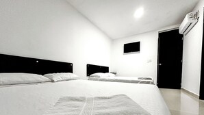 Habitación de hotel con una cama grande, una cama más pequeña y un escritorio.