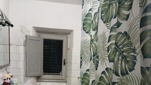 A bathroom with a sink, toilet, and shower curtain with a leaf pattern.