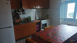 A compact kitchen with wooden cabinets, a white stove, and a dining table with a floral tablecloth.