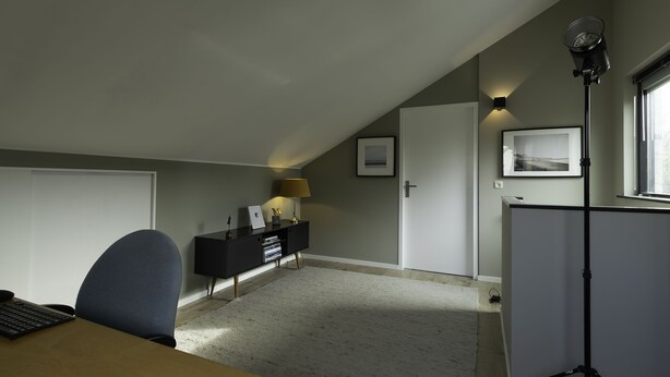A room with a desk, chair, black console, lamp, framed picture, and a standing lamp. - Komfortabel Eingerichtetes Ferienhaus mit Herrlichem Sonnige Terrasse (Heiloo)