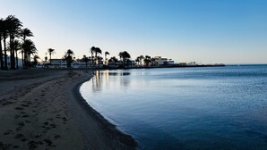 En strand med sandet bredde, palmer og et roligt hav.