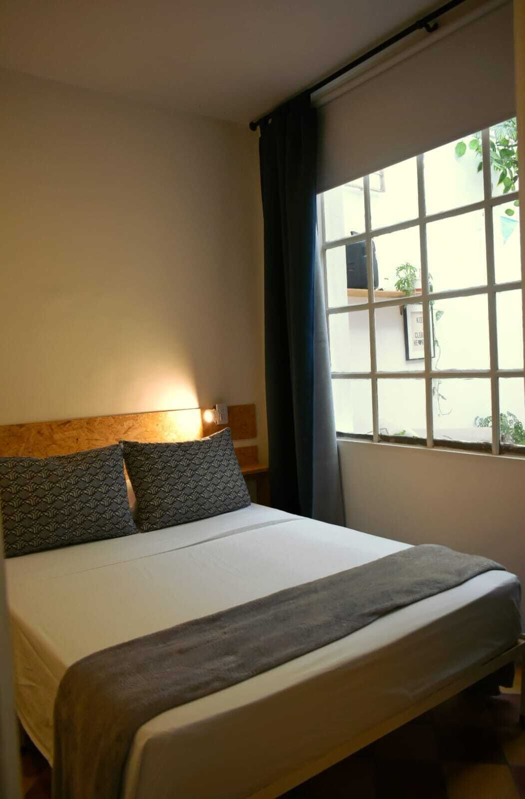 Ein Hotelzimmer mit einem Bett, einem Vorhangfenster und einer Wandlampe.