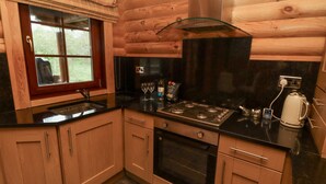 A compact kitchen with wooden cabinetry, a gas stove, an oven, and a black countertop. - 24 Lakeside Drive (Morpeth)