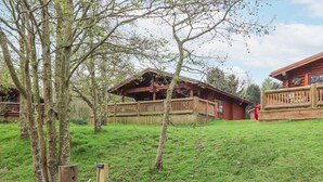 A rustic cabin with a wooden deck and a fenced yard. - 24 Lakeside Drive (Morpeth)