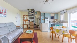 A modern apartment with a living room, dining area, kitchen, and a spiral staircase. - Un Balcon sur le Port - Place de parking (Courseulles-sur-Mer)