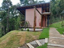 A modern building with a pink exterior, a wooden deck, and a hammock.