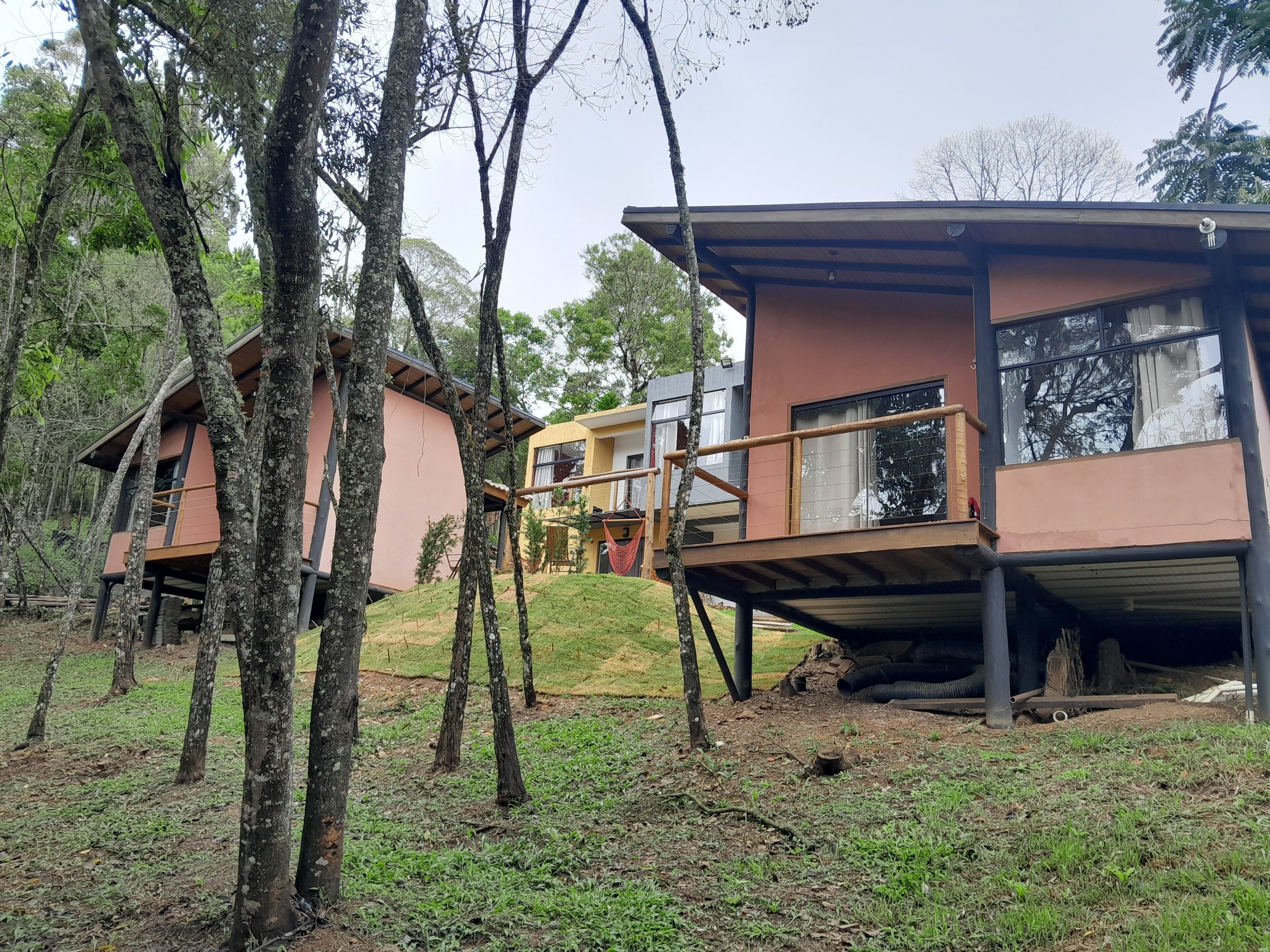 Ein modernes Baumhaus-ähnliches Gebäude mit einer Holzterrasse und einer Hängematte.