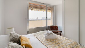Ein Hotelzimmer mit Bett, Sessel, Fenster mit Blick und Lampe.
