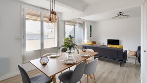 Ein modernes Wohnzimmer mit Essbereich, großen Fenstern und Blick auf die Stadt.
