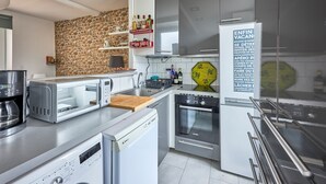 Une cuisine moderne avec un mur en briques, des appareils électroménagers en acier inoxydable et un meuble à vin intégré.
