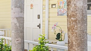 A yellow building with a white door, a no smoking sign, and a bicycle mural. - Prime Downtown Key West Spot - The Cozy Little Cottage! (Key West)