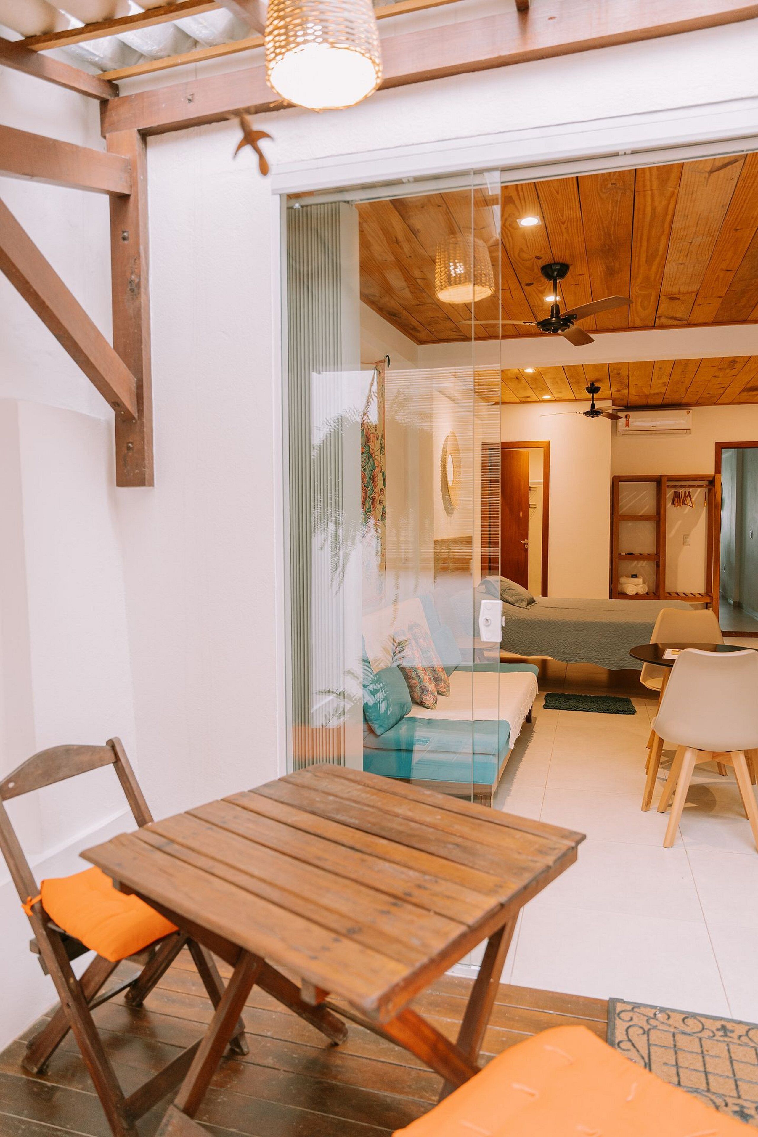 A cozy room with a wooden table and chairs, a bed, and a ceiling fan.