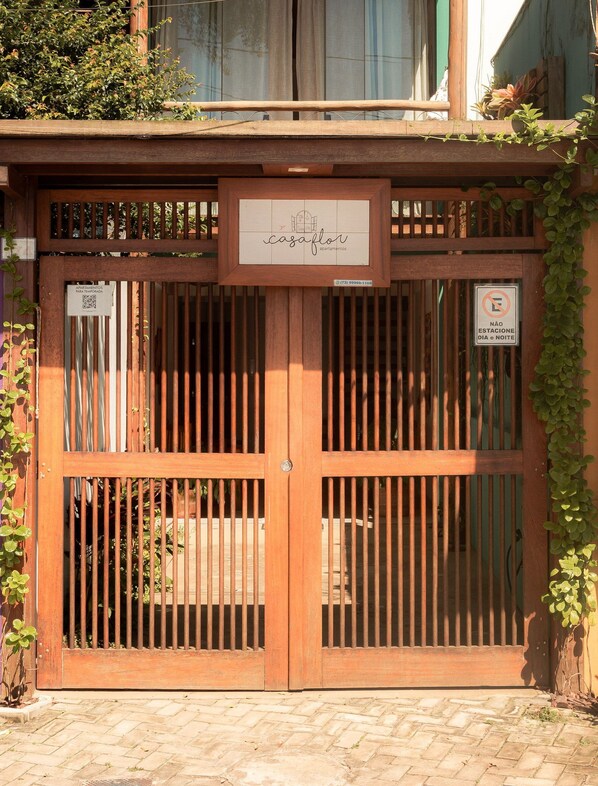 A wooden gate with a sign for 'casa flor apartments' and a no parking sign.