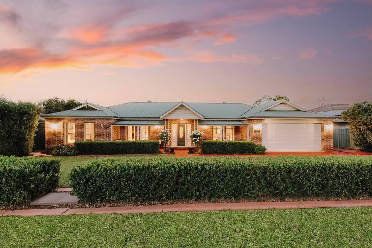 A manicured front garden and lush front lawn welcomes you into this charming home and highlights the immaculately kept garden details.