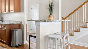 A modern kitchen with wooden cabinets, a stainless steel refrigerator, and a white island with bar stools.