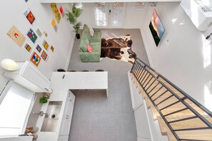A modern apartment with a green sofa, a cowhide rug, and a staircase.