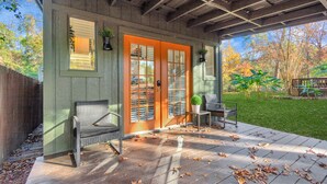 Eine überdachte Veranda mit Holzterrasse, zwei Stühlen und einem kleinen Tisch.