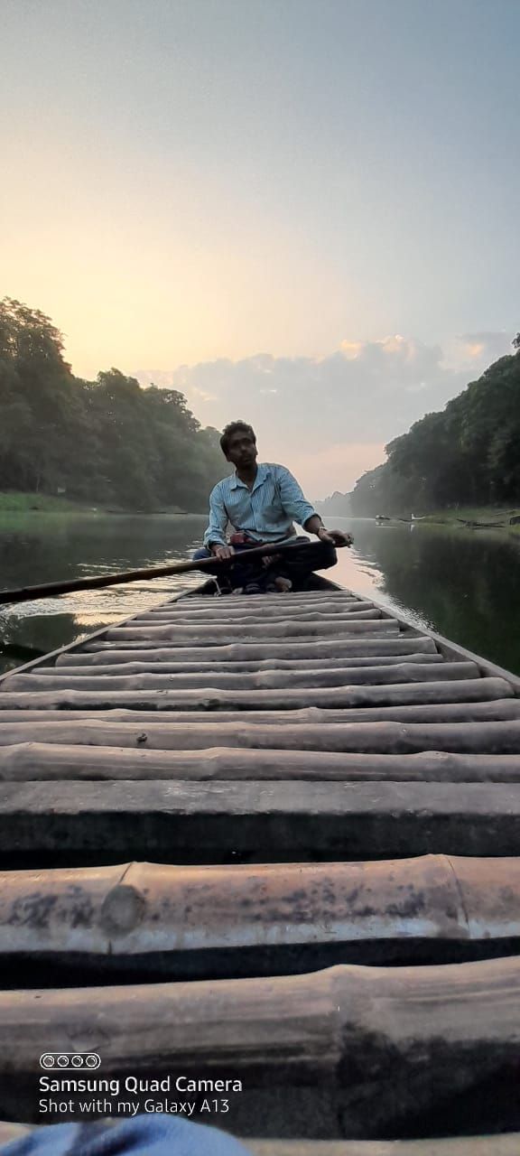 A person rowing a boat on a wooden bridge over a calm river.