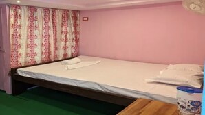 A single bed with a wooden frame, a green carpet, and a pink wall. - Resort Ichche Kuthi by Urban Express (Bangaon)