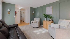 Una sala de estar con sofá, sillón y una mesita auxiliar con una planta.