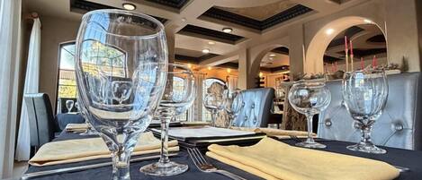 A dining area with tables set for two, featuring clear glassware and a dark tablecloth.
