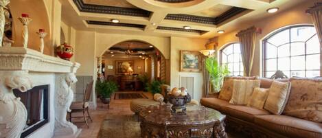 A spacious living room with a fireplace, ornate ceiling, and comfortable seating.