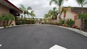 A parking lot with directional arrows, surrounded by palm trees and flower beds. - Budget Inn Anaheim (Anaheim)