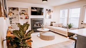 A modern living room with a fireplace, a sofa, a coffee table, and a TV mounted above the fireplace.