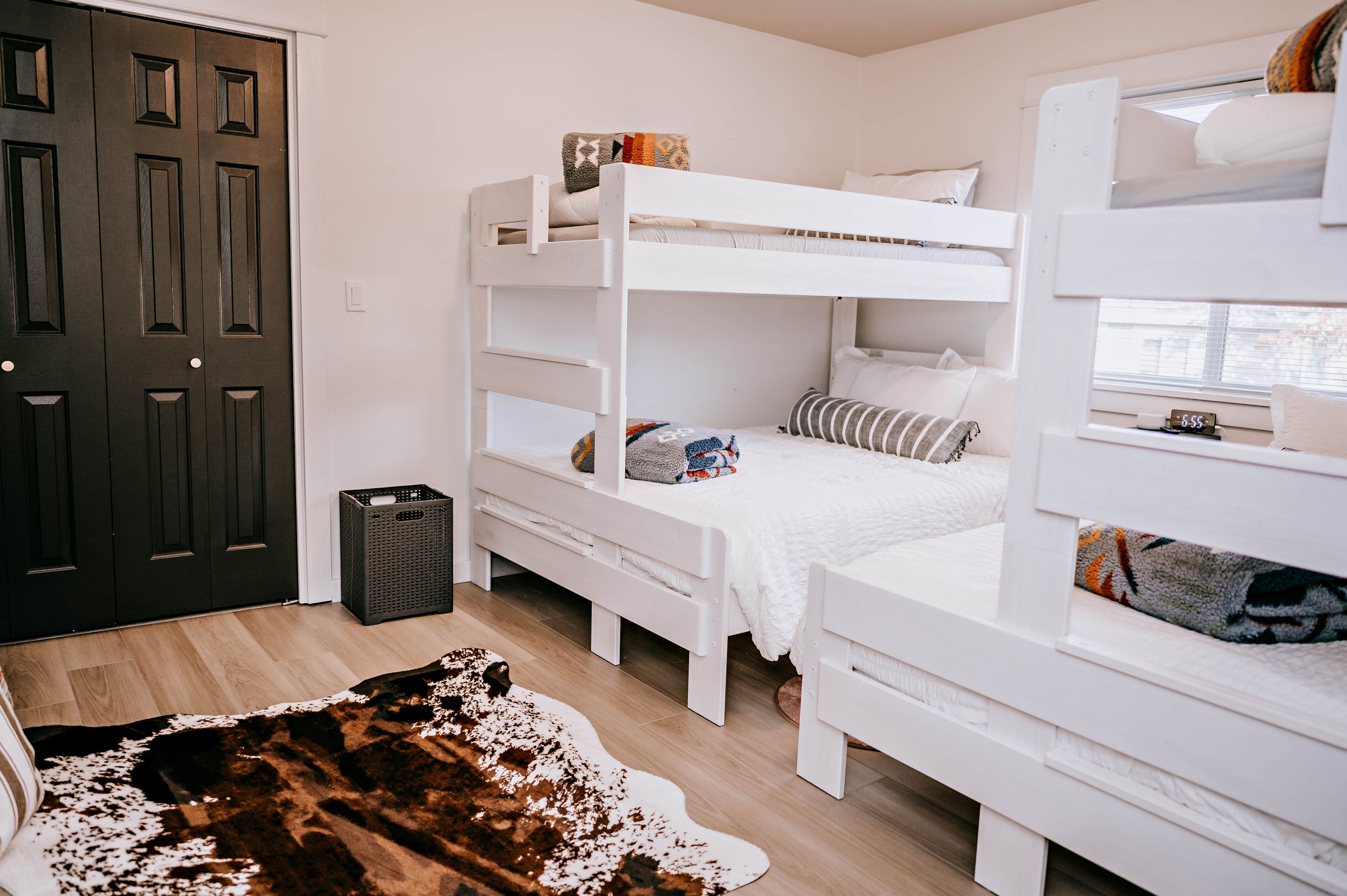 A room with bunk beds, a door, a basket, and a cowhide rug.