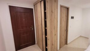 A room with a wooden wardrobe, a door, and a small white wall-mounted light fixture. - Aparta Estudio Para Nómadas Digitales en Laureles (Medellín)