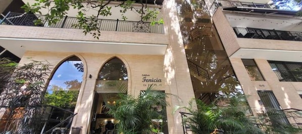 Hotel Fenicia features a striking entrance with three arched doorways and lush greenery surrounding the property.