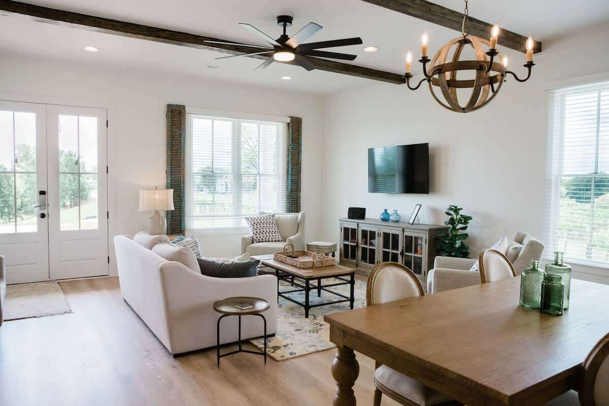 Un salon spacieux avec un canapé blanc, une table basse en bois et une table à manger avec des chaises.