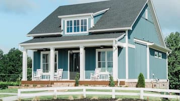 A two-story house with a porch, a garage, and a fenced yard.