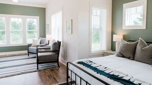 Ein Schlafzimmer mit Bett, einem Sessel, einem Fenster und einem Deckenventilator.