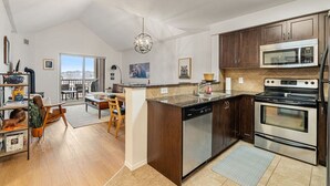 Een moderne keuken met een centraal eiland, roestvrijstalen apparatuur en een eethoek met uitzicht.