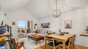 Een ruime woonkamer met een eettafel, een bank en een groot raam met uitzicht.