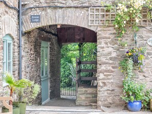 A stone building with a sign reading 'Rowan Lodge,' a wooden gate, and potted plants. - 5 bedroom accommodation in Slapton (Slapton)