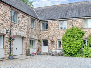 A stone building with a gravel courtyard, outdoor seating, and hanging flower baskets. - 5 bedroom accommodation in Slapton (Slapton)